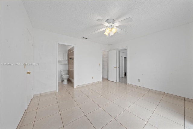 tiled empty room featuring ceiling fan and a textured ceiling