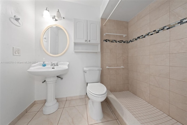 bathroom with toilet, tile patterned floors, and tiled shower