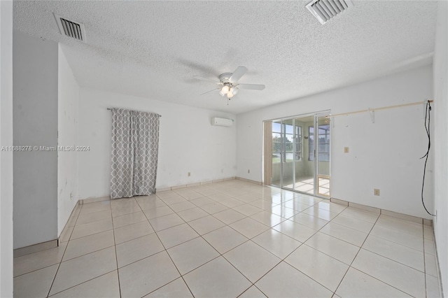 tiled spare room with a wall unit AC, a textured ceiling, and ceiling fan