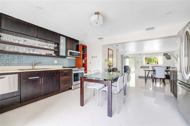 kitchen featuring tasteful backsplash, appliances with stainless steel finishes, dark brown cabinets, light tile patterned floors, and sink