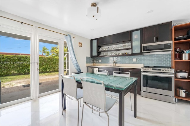 kitchen featuring sink, appliances with stainless steel finishes, light tile patterned floors, backsplash, and dark brown cabinets