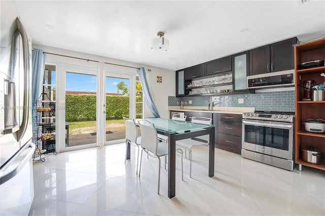 kitchen with backsplash, sink, light tile patterned flooring, and stainless steel appliances