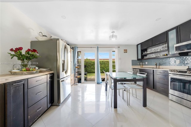 kitchen featuring appliances with stainless steel finishes, light tile patterned floors, sink, and backsplash