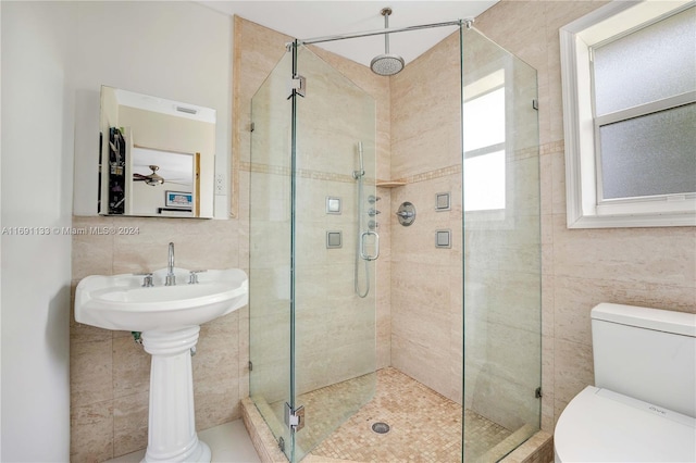 bathroom featuring tile walls, toilet, and a shower with door