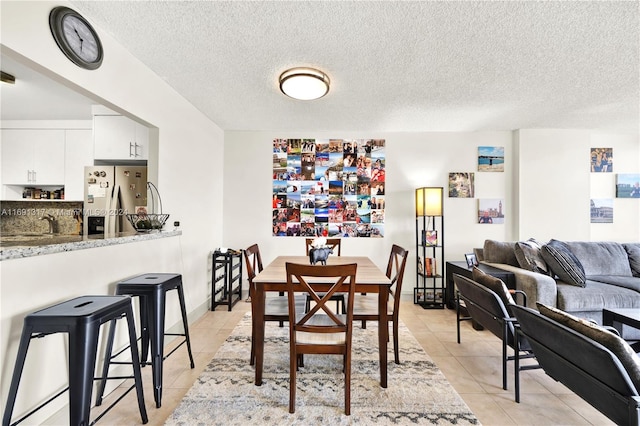 dining area featuring a textured ceiling, light tile patterned floors, and sink