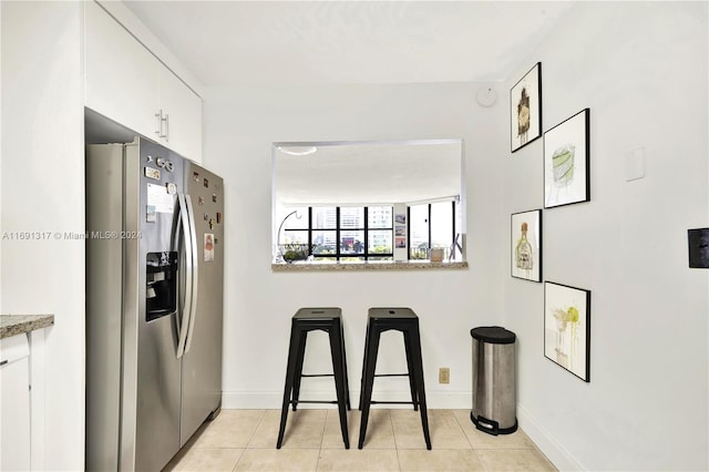 kitchen with white cabinetry, light tile patterned floors, and stainless steel fridge