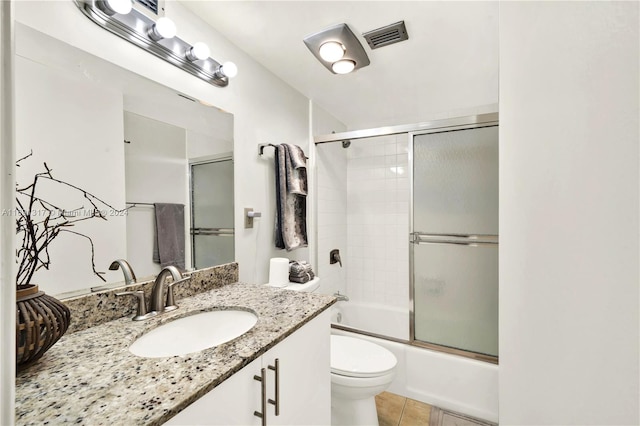 full bathroom featuring toilet, vanity, bath / shower combo with glass door, and tile patterned floors