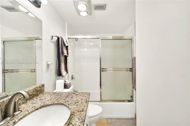 full bathroom with bath / shower combo with glass door, vanity, toilet, and tile patterned flooring