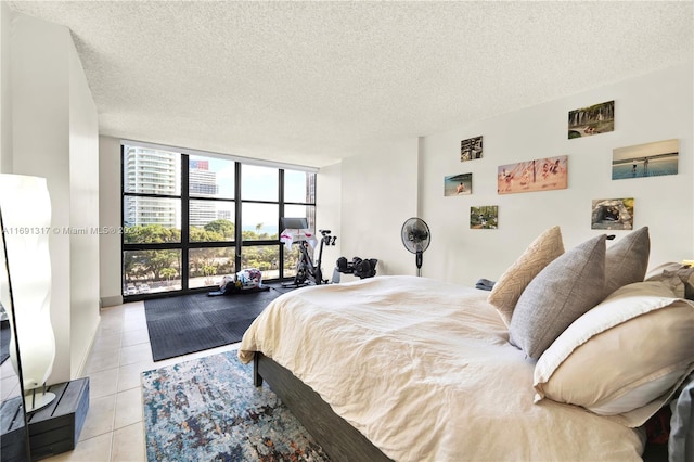 tiled bedroom with access to exterior, expansive windows, and a textured ceiling