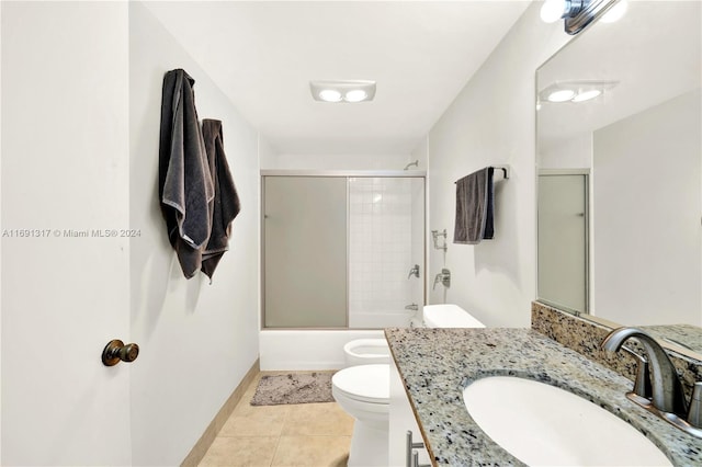 full bathroom with vanity, bath / shower combo with glass door, tile patterned flooring, and toilet