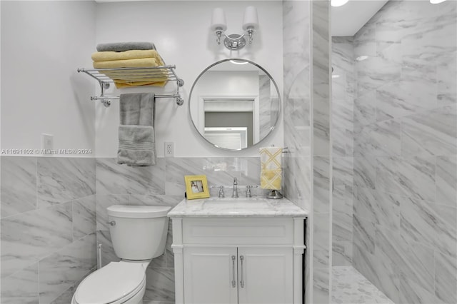 bathroom with tiled shower, vanity, tile walls, and toilet