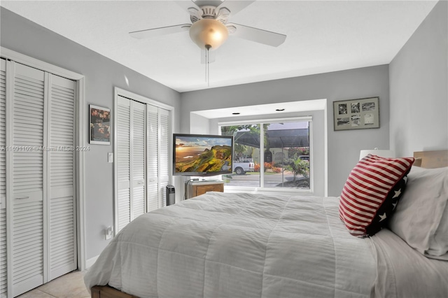 bedroom featuring ceiling fan, light tile patterned floors, and multiple closets