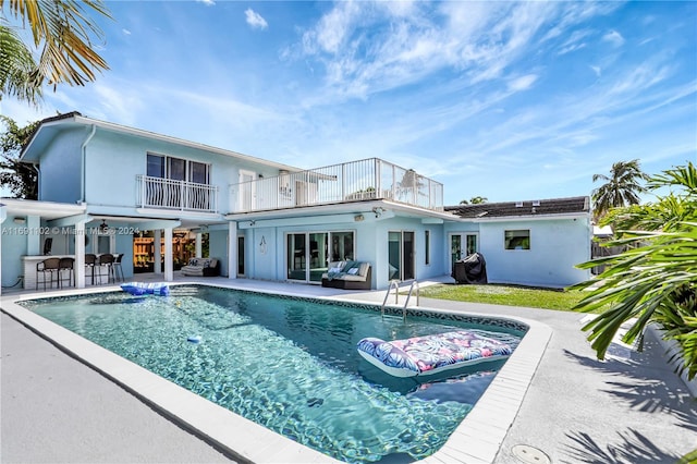 back of property featuring a patio area, a balcony, and a bar