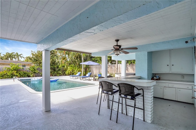 view of pool with exterior bar, a patio, and ceiling fan