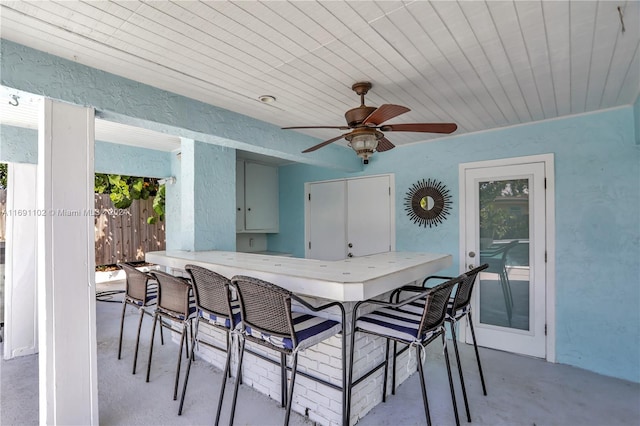 view of patio with ceiling fan and an outdoor bar