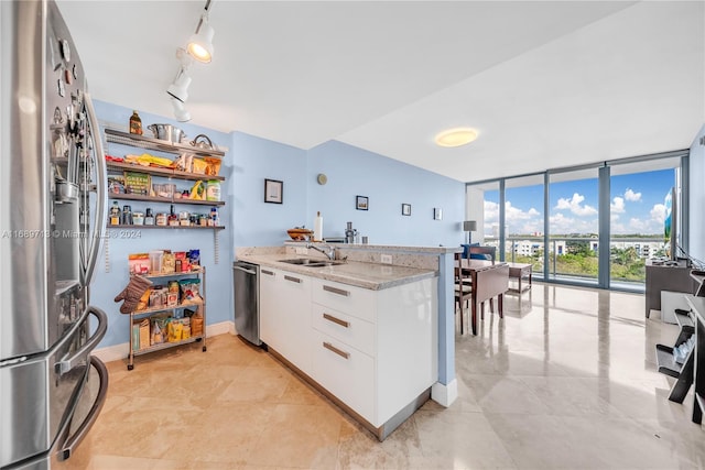 kitchen featuring white cabinets, stainless steel appliances, light stone counters, and floor to ceiling windows