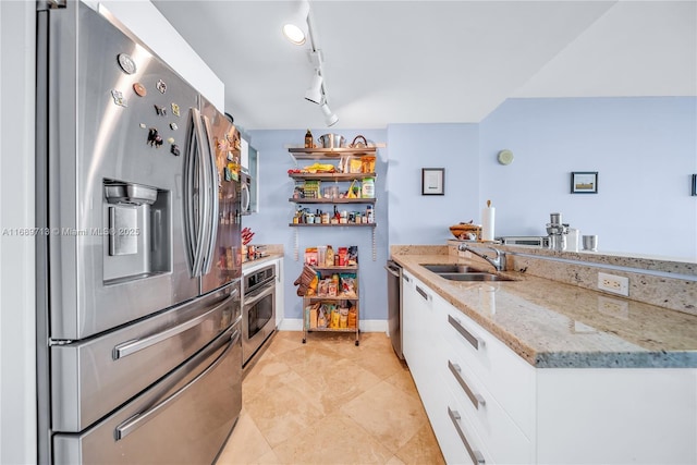 kitchen featuring sink, light stone counters, appliances with stainless steel finishes, white cabinets, and rail lighting