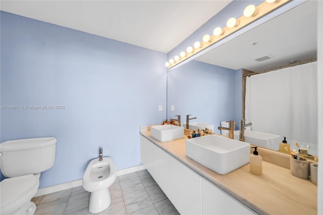 bathroom with toilet, vanity, curtained shower, and a bidet