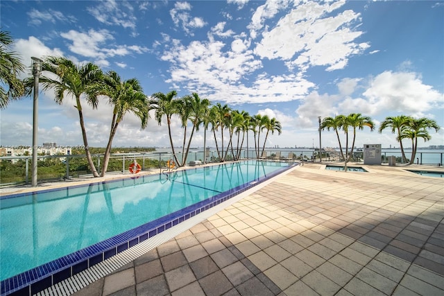 view of swimming pool featuring a patio and a water view