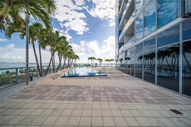 view of pool with a water view and a patio area