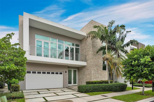 view of front of home featuring concrete driveway, french doors, a garage, and stucco siding