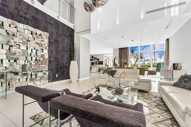 living room with visible vents, an accent wall, baseboards, floor to ceiling windows, and a high ceiling