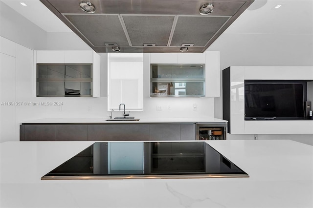 kitchen with wine cooler, white cabinetry, sink, and black electric stovetop