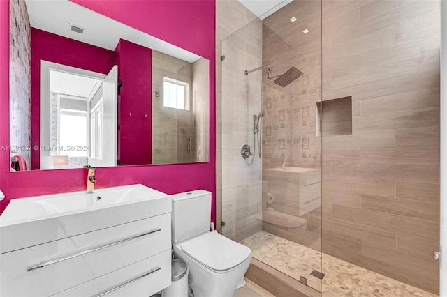 bathroom featuring toilet, vanity, and a tile shower