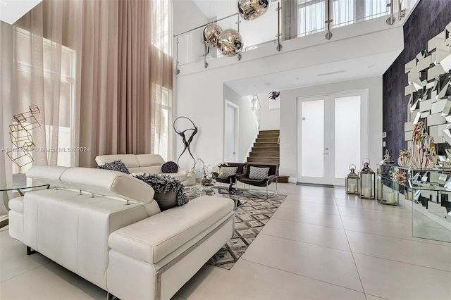 living room with french doors, a towering ceiling, and light tile patterned flooring