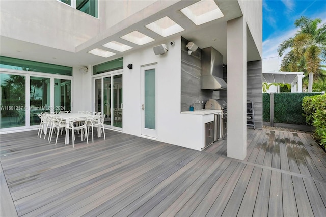 wooden deck with an outdoor kitchen, sink, and a grill