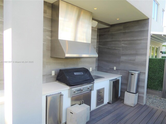 exterior space featuring stainless steel fridge, wall chimney range hood, light hardwood / wood-style flooring, and tile walls