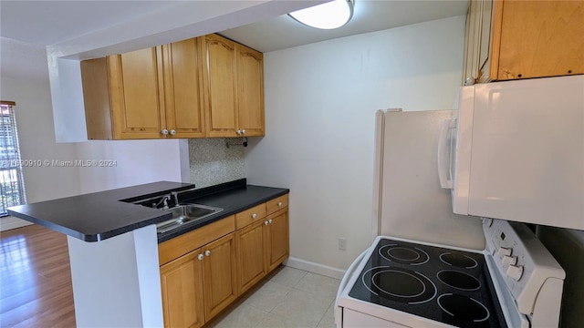 kitchen featuring electric range, sink, a kitchen breakfast bar, kitchen peninsula, and decorative backsplash