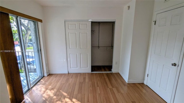 unfurnished bedroom with light hardwood / wood-style floors, access to outside, and a closet