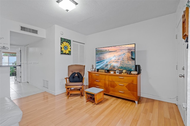 living area featuring light hardwood / wood-style floors and a textured ceiling