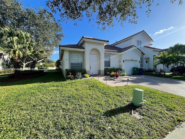 mediterranean / spanish home featuring a tiled roof, a front yard, stucco siding, decorative driveway, and an attached garage