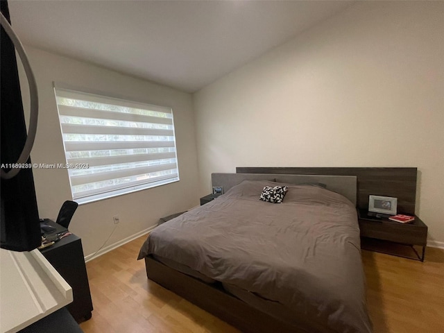 bedroom with light wood-type flooring and vaulted ceiling