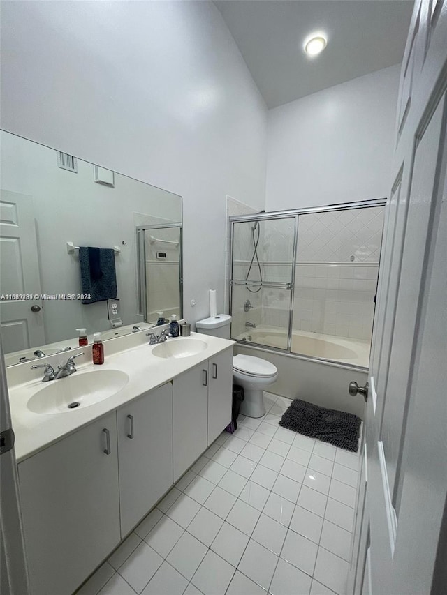 full bathroom featuring toilet, vanity, bath / shower combo with glass door, and tile patterned flooring