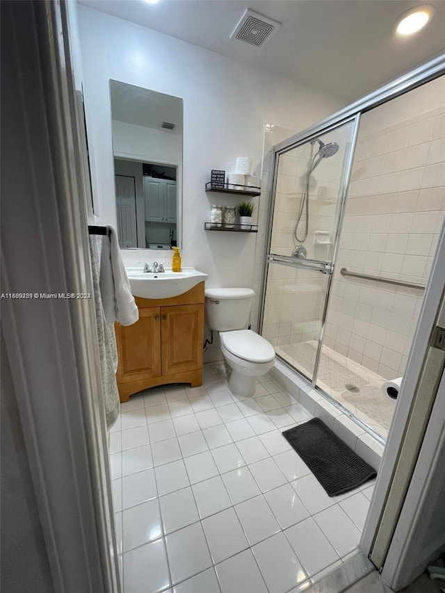 bathroom featuring toilet, tile patterned floors, and a shower with door