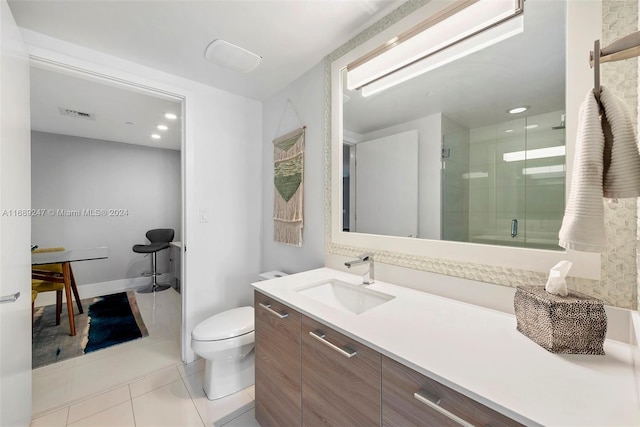 bathroom featuring toilet, vanity, tile patterned flooring, and a shower with door