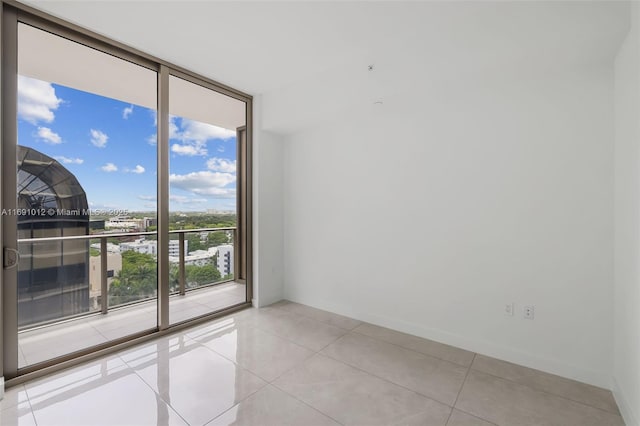 spare room featuring a wall of windows and light tile patterned flooring