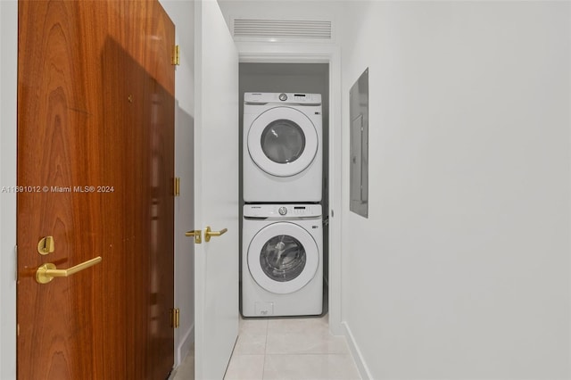 laundry area featuring stacked washer / drying machine and light tile patterned floors