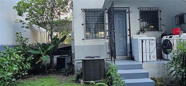 doorway to property with separate washer and dryer and central air condition unit