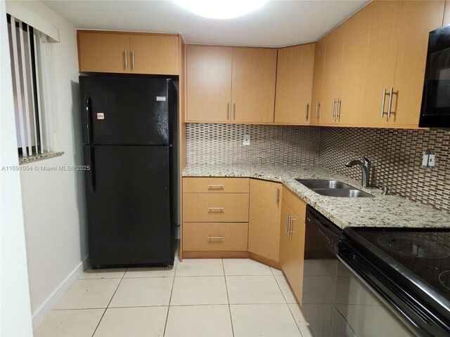 kitchen featuring light stone countertops, backsplash, sink, black appliances, and light tile patterned floors