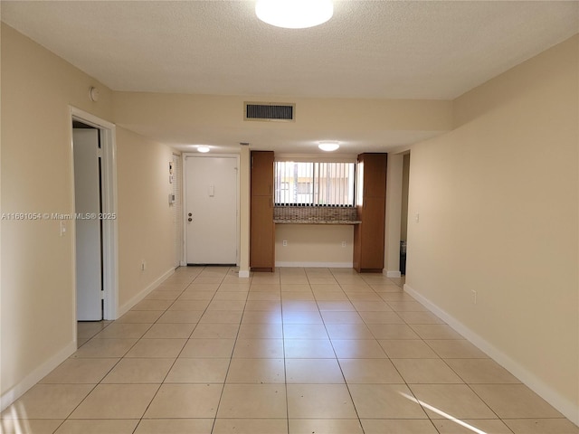 unfurnished room with a textured ceiling and light tile patterned floors