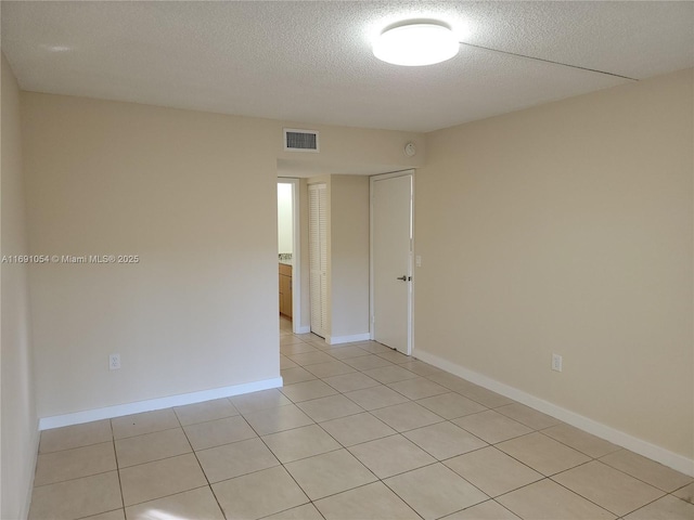 tiled empty room with a textured ceiling