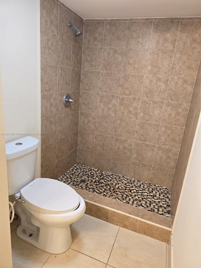 bathroom featuring a tile shower, tile patterned floors, and toilet