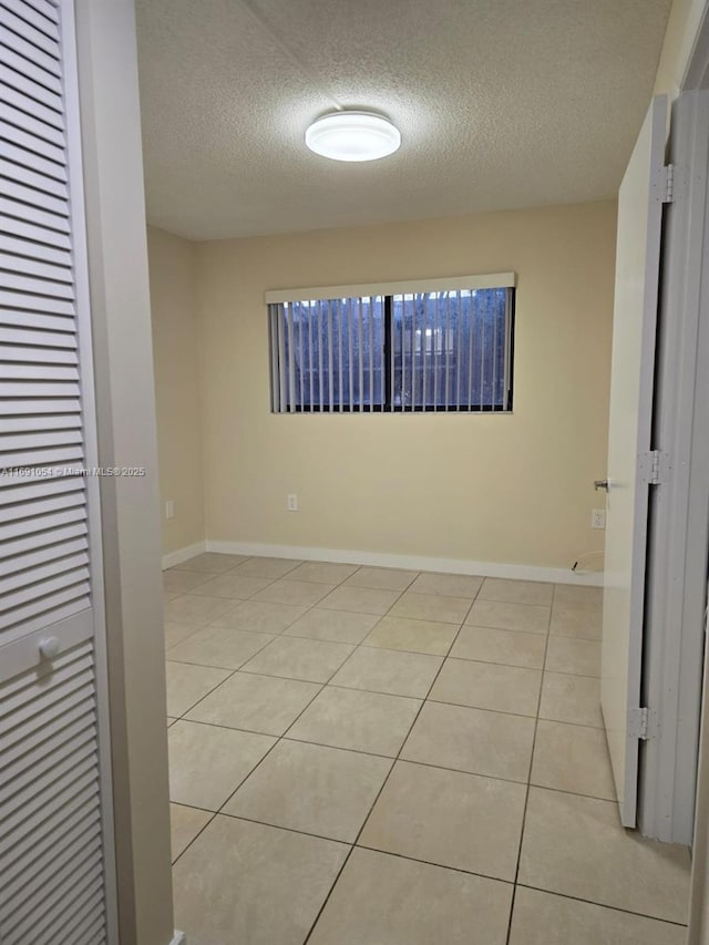 spare room featuring a textured ceiling and light tile patterned flooring