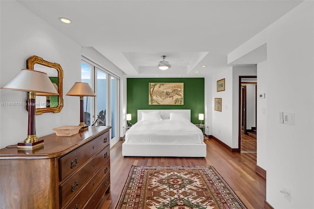 bedroom featuring hardwood / wood-style flooring, a raised ceiling, and ceiling fan