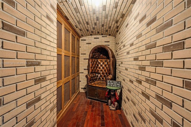 wine cellar featuring dark hardwood / wood-style floors, brick wall, and lofted ceiling