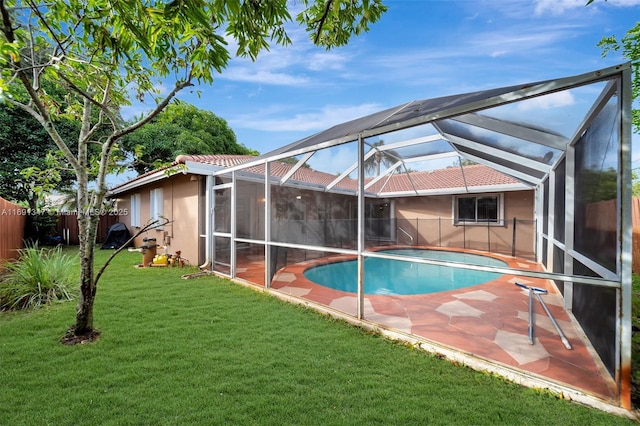 view of pool with glass enclosure, a lawn, and a patio